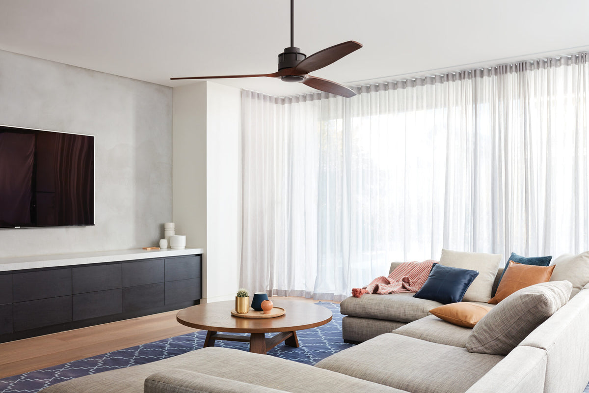 Akmani ceiling fan with dark timber blades in a bright living room with a navy rug and low timber coffee table