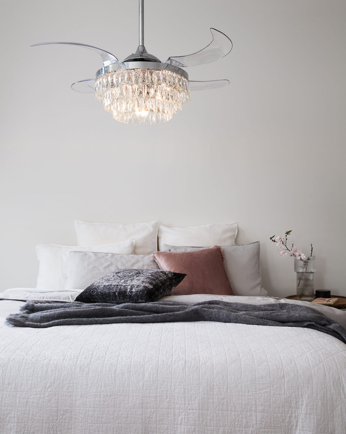 Fanaway chrome ceiling fan with crystal light and retractable clear blades above a bed