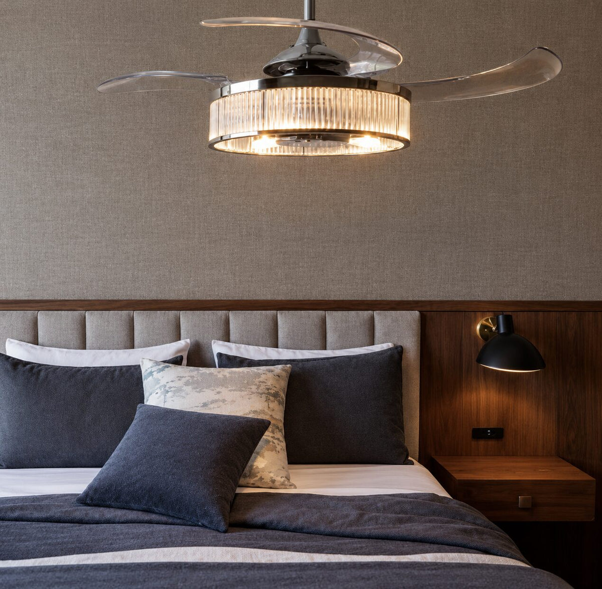 Fanaway chrome ceiling fan with a ribbed glass light above a bed with navy and cream cushions