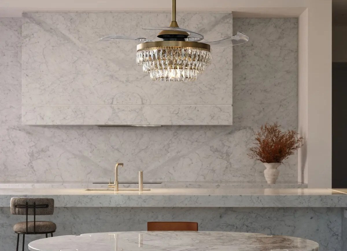 Brass and crystal retractable-blade ceiling fan above a round marble table in a marble kitchen