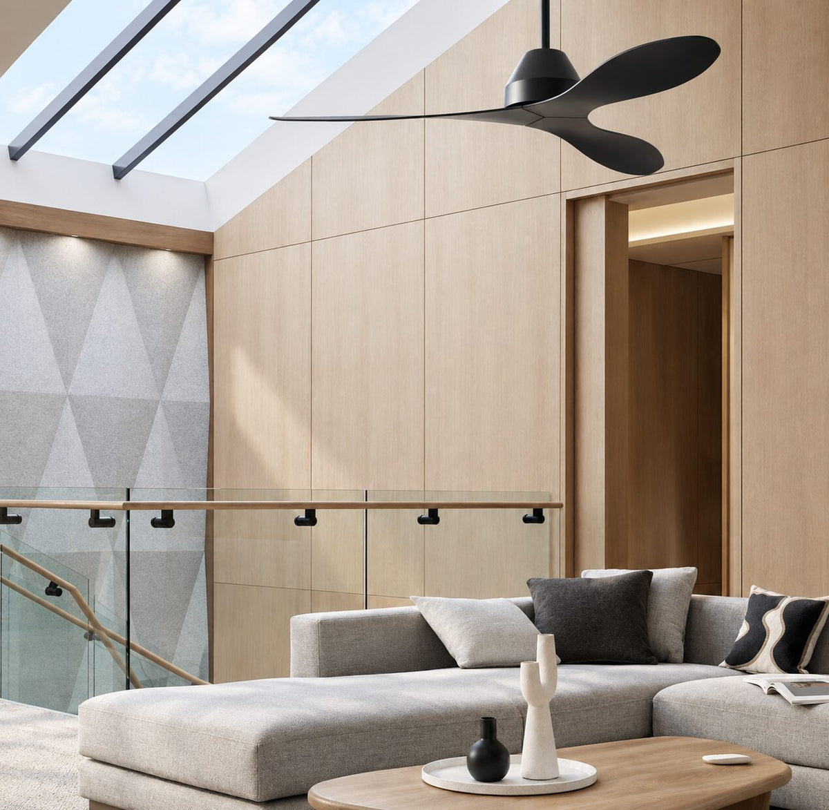 Slim black flush mount ceiling fan in a sloped-ceiling lounge with a grey sectional sofa
