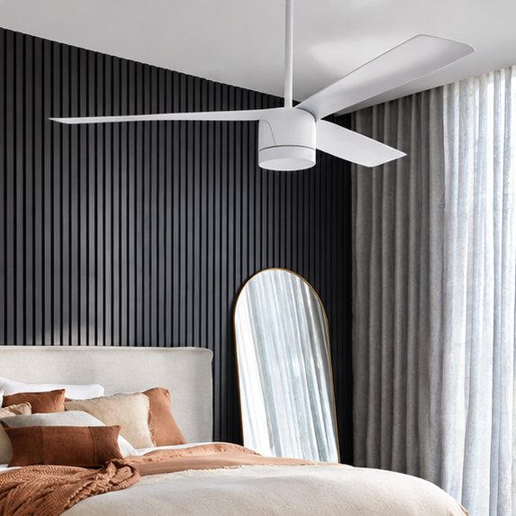 White three-blade ceiling fan above a bed with terracotta and cream bedding in front of a charcoal slatted wall and grey curtains
