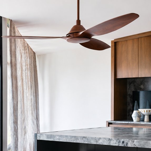 Copper-finish ceiling fan with three timber-look blades in a bright room with timber cabinetry and a marble benchtop