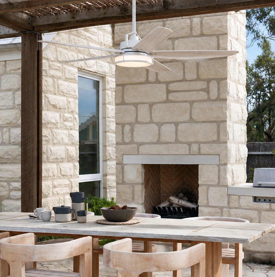 White outdoor ceiling fan with whitewashed blades above a dining table in front of a stone fireplace on a covered patio